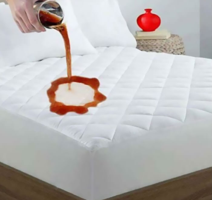 This mattress pad promises to protect your bed from giant disembodied hands that pour old soda onto invisible flat surfaces in this photo.