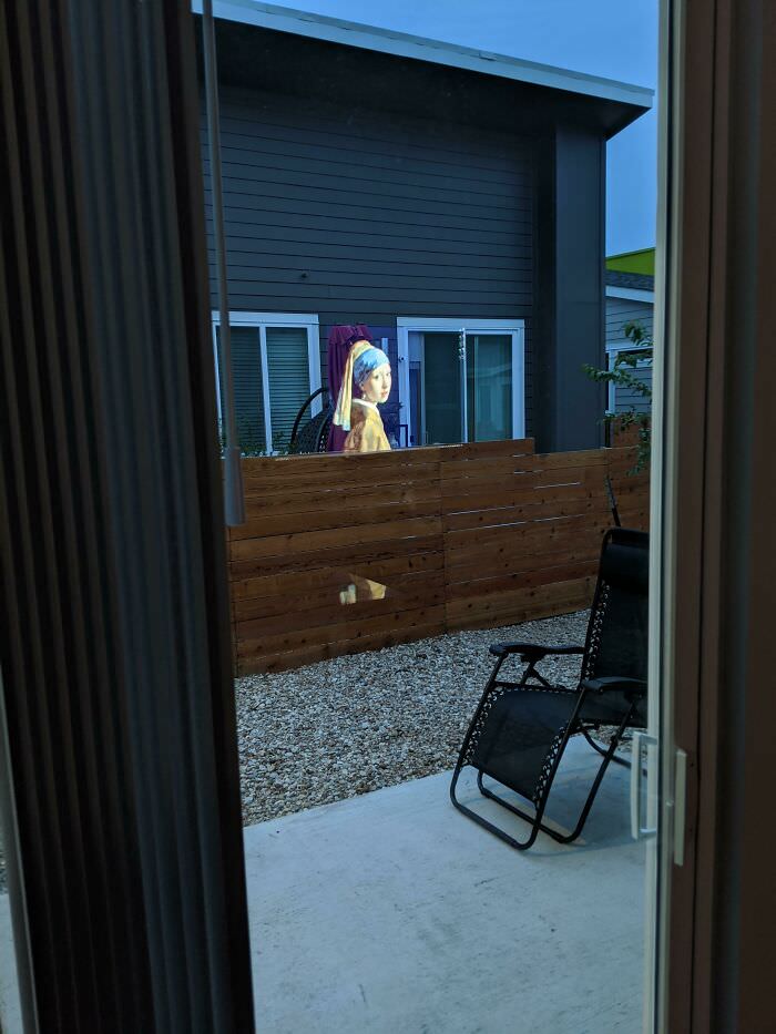 The reflection of a TV that makes it look like "Girl with the Pearl Earring" is in a backyard.
