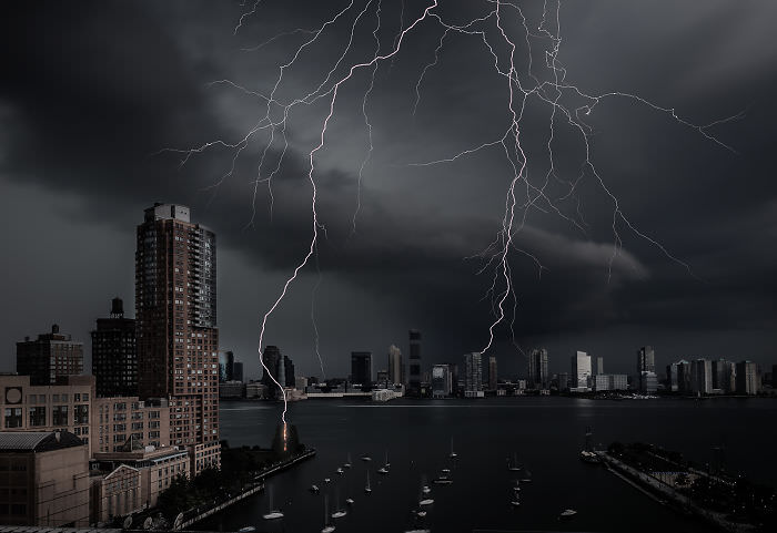 A massive lightning strike completely spanning the Hudson River in New York City.
