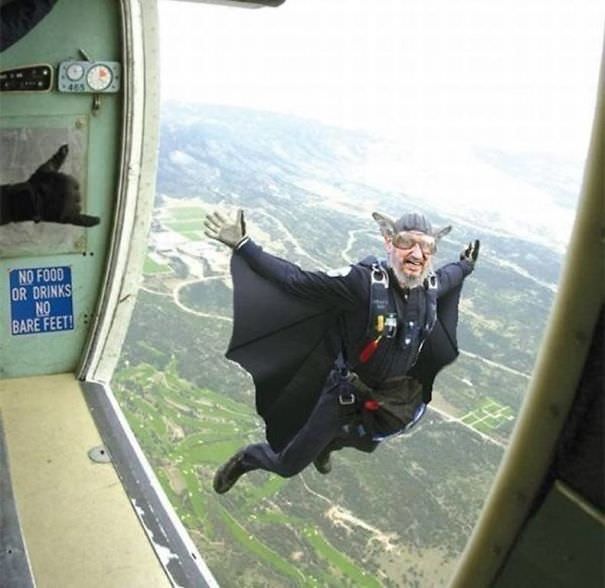 An elderly man in a wingsuit resembling Batman jumps out of a plane.