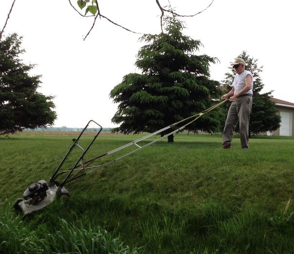 A 91-year-old grandpa mows his ditch banks with a mower handle extender like a boss.