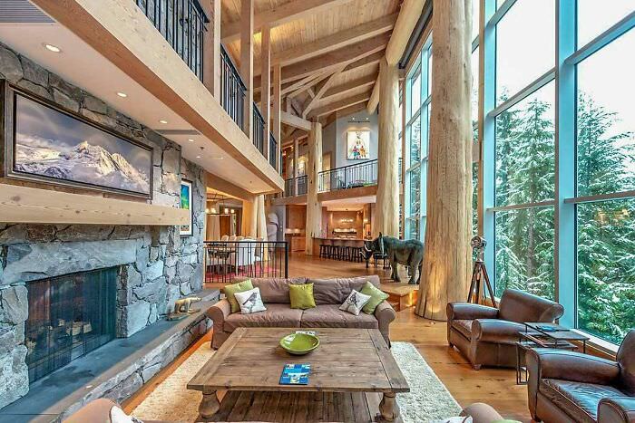 A living area with a glass wall and cedar-log posts and beams in a ski retreat located in Whistler, British Columbia