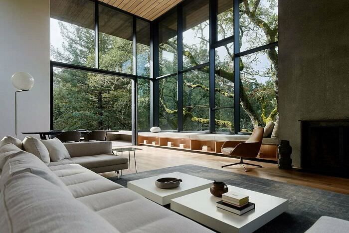 A tall and spacious living room opening up to a patio and garden surrounded by mature oak trees in Orinda, Contra Costa County, California