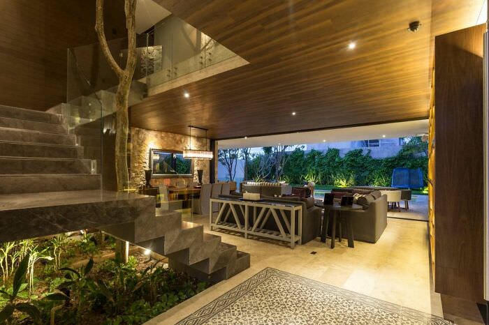Stone and glass elements merge with green surroundings in a home located in Mérida, Mexico.