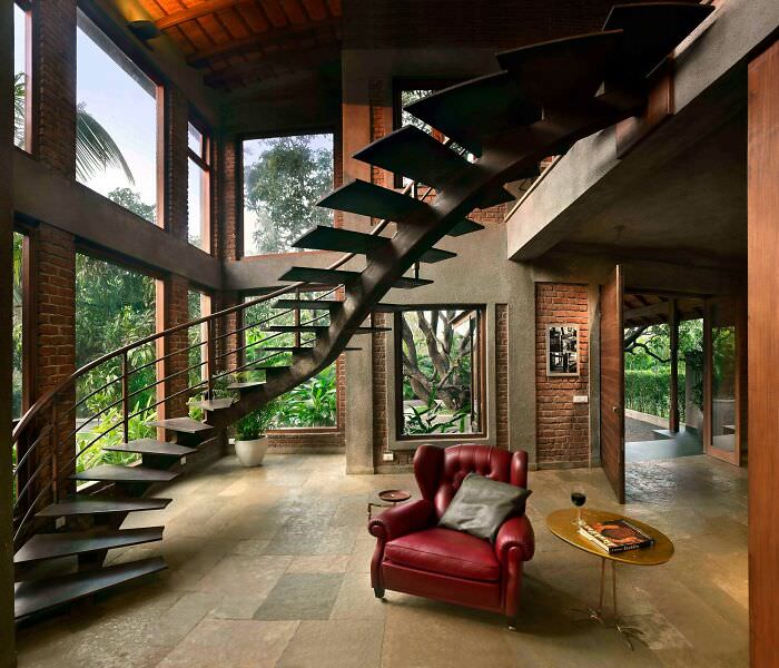 A unique entrance to a brick residence surrounded by old mango trees, featuring a twisting steel staircase in Alibag near Mumbai, India.
