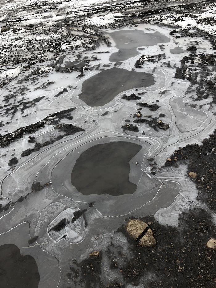 A frozen puddle in a backyard that looks like a landscape from the perspective of a plane.
