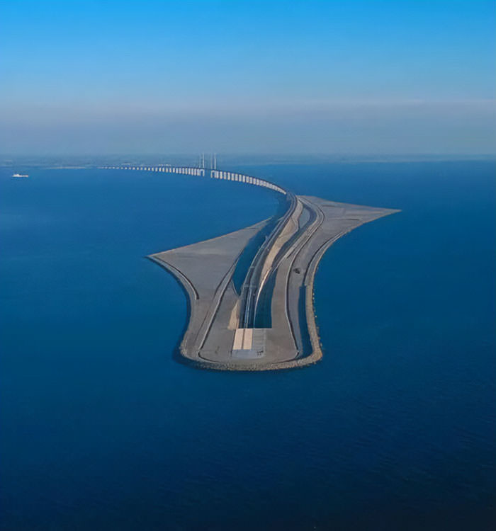 The bridge from Sweden transforms into an underwater tunnel that resurfaces in Denmark, connecting both countries through this magnificent engineering marvel.