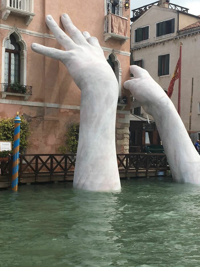 Giant hands emerge from a Venice canal