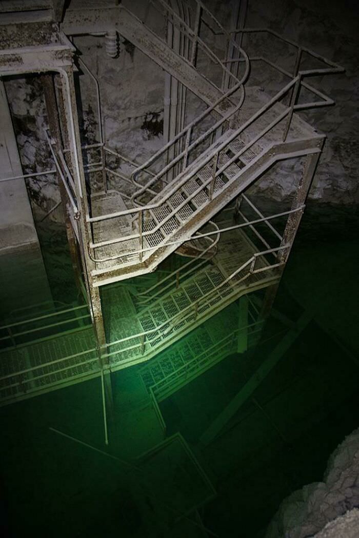 Stairs leading down to flooded machinery deep inside a mine