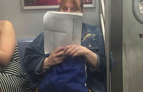 A woman on the subway printed out 15 pages of Facebook posts and is just reading the comments.