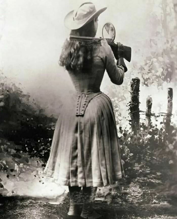 Sharpshooter, Annie Oakley, shooting over her shoulder using a hand mirror, 1899.