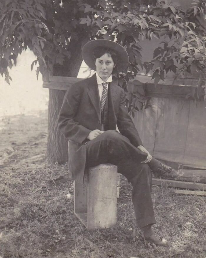 An Edwardian woman dressed the part of a handsome dandy writes a message to her lover, "Hello Kid:- How you be?