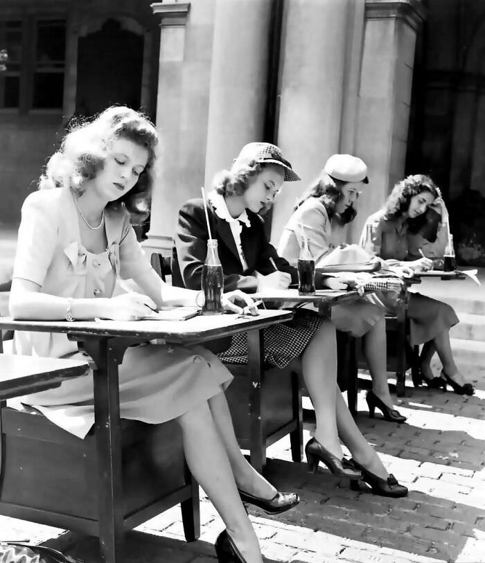A group of 1940s students doing their schoolwork while drinking some Coca Cola.
