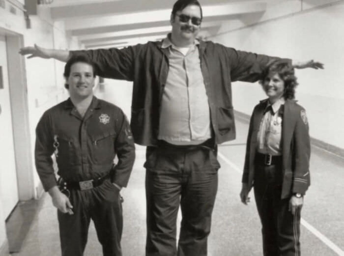 Two prison guards posing for a photo with Ed Kemper, who was 6'9" and 300 lbs.