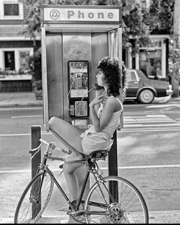 Woman talking on a payphone, 1980s.