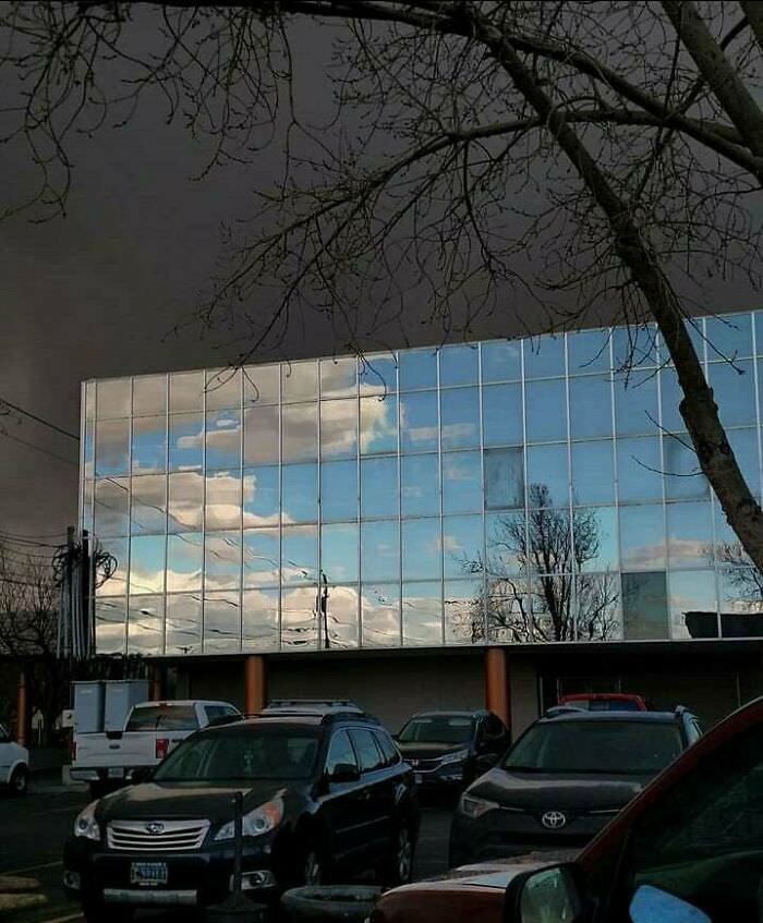 Blue sky reflecting on a neighboring building with a storm behind it.